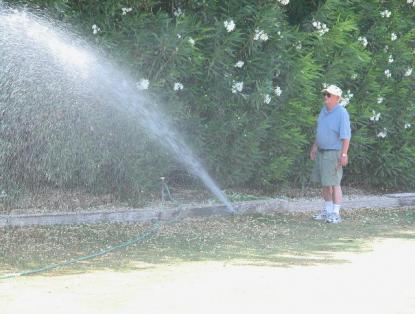 Carlsbad sprinkler repair technician examines new sprinkler head throw distance